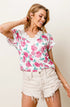 Woman wearing a floral top and denim shorts against a plain background