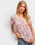 Woman wearing a floral short-sleeve top against a plain background