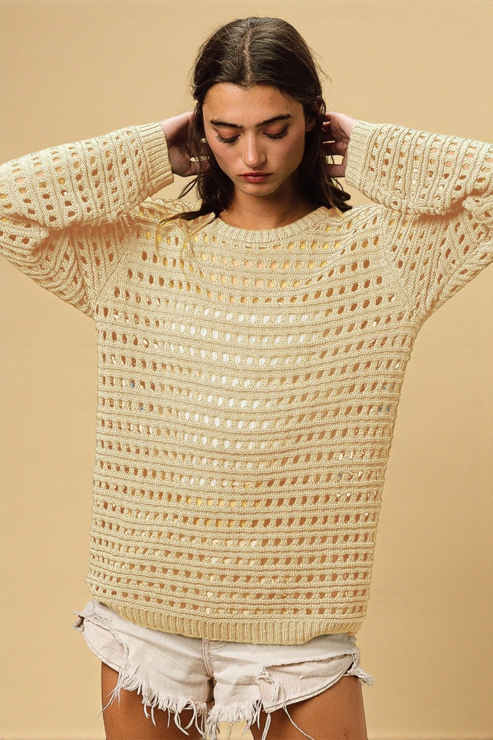 Woman wearing a beige knitted sweater against a beige background