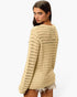A woman wearing a beige open-knit long-sleeve sweater, shown from a back-three-quarter angle against a plain white studio background.