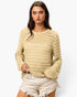 A woman modeling a cream-colored open-knit long-sleeve sweater paired with light-wash frayed denim shorts against a plain white background.