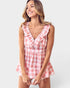 Woman wearing a pink and white checkered dress on a plain background
