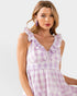 Woman wearing a purple checkered dress with ruffled straps on a white background