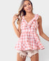 Woman wearing a pink and white checkered top with ruffles on a light gray background