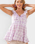 Woman wearing a purple and white checkered top with ruffled details on a plain background