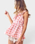 Woman wearing a pink and white checkered top with a plain background