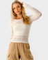 Woman wearing a beige lace top and beige cargo pants on a light gray background