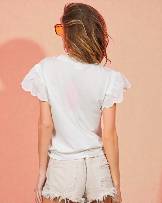 Person wearing a white ruffled top and light shorts against a pink background