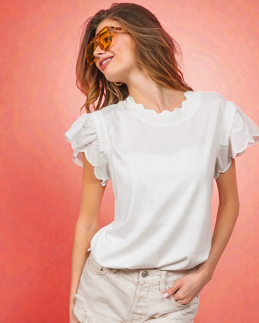 Woman wearing a white blouse with ruffled sleeves against a pink background