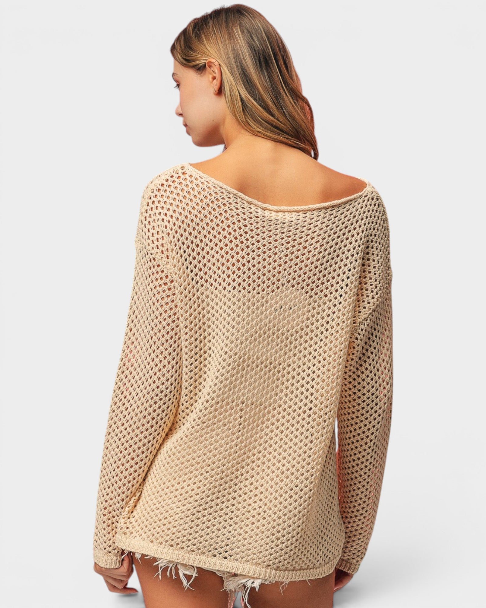 Beige knitted sweater worn by a person on a white background