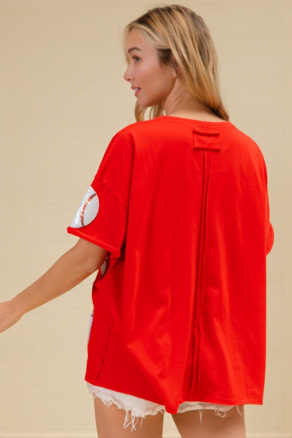 Woman wearing a red oversized shirt with a beige background