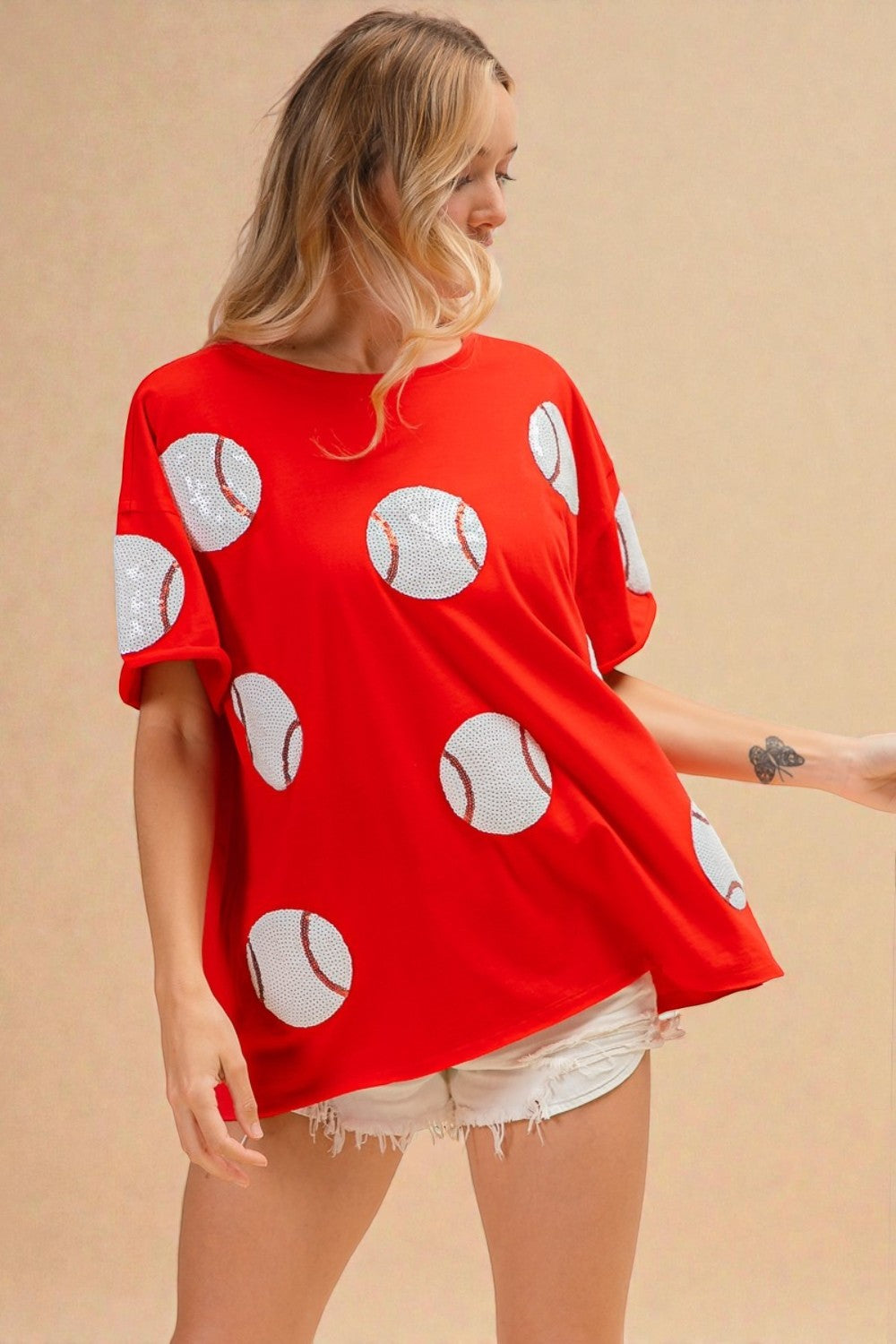 Woman wearing a red oversized t-shirt with white polka dot patterns on a beige background