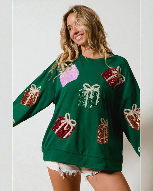 Woman wearing a green sweater with decorative gift patterns on a plain background