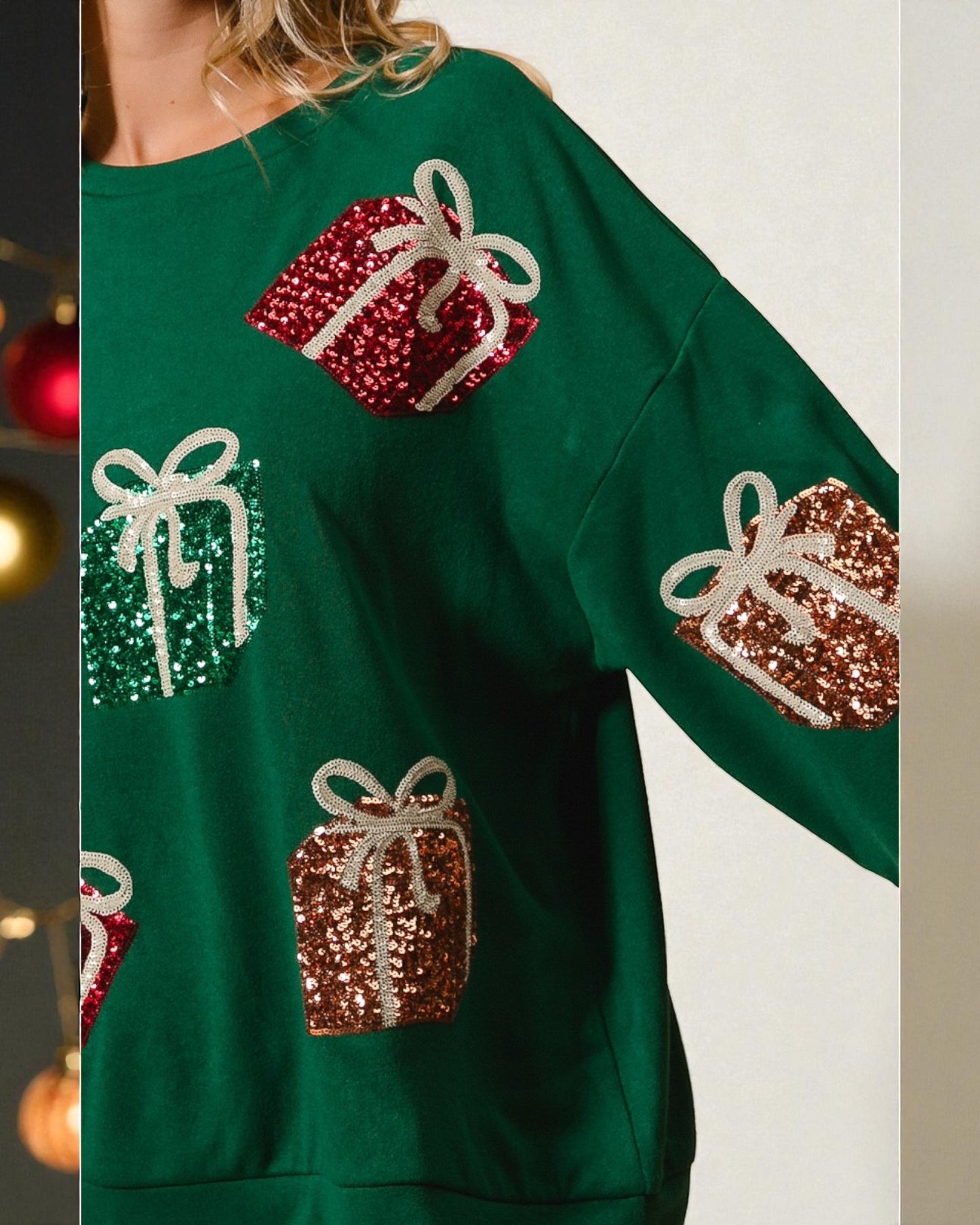 Green sweater with sequin gift box designs on a neutral background