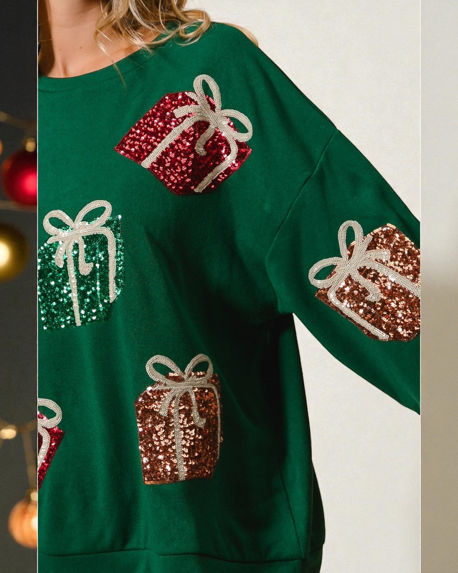Green sweater with sequin gift box designs on a neutral background