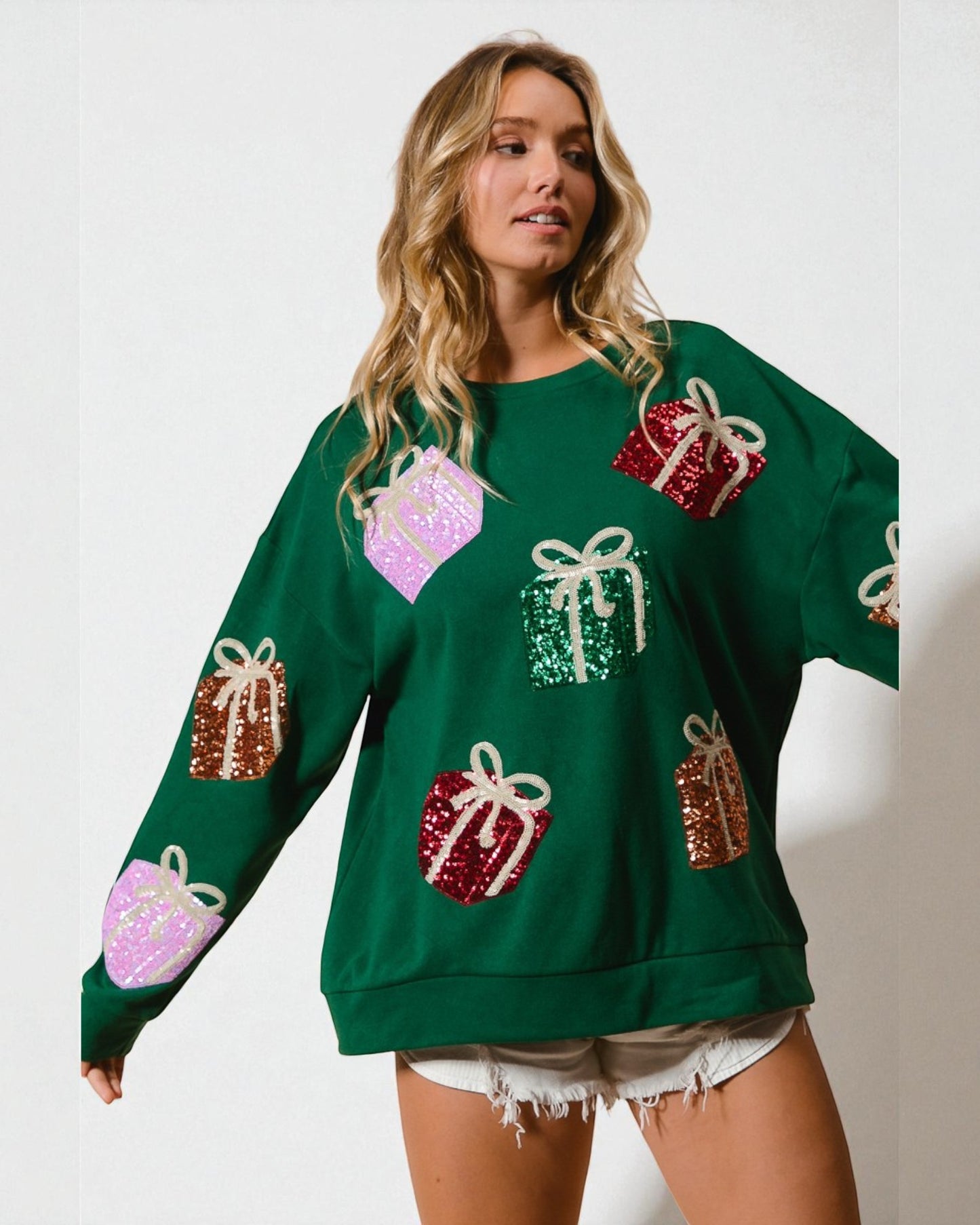 Woman wearing a green sweater with colorful gift box patterns on a white background