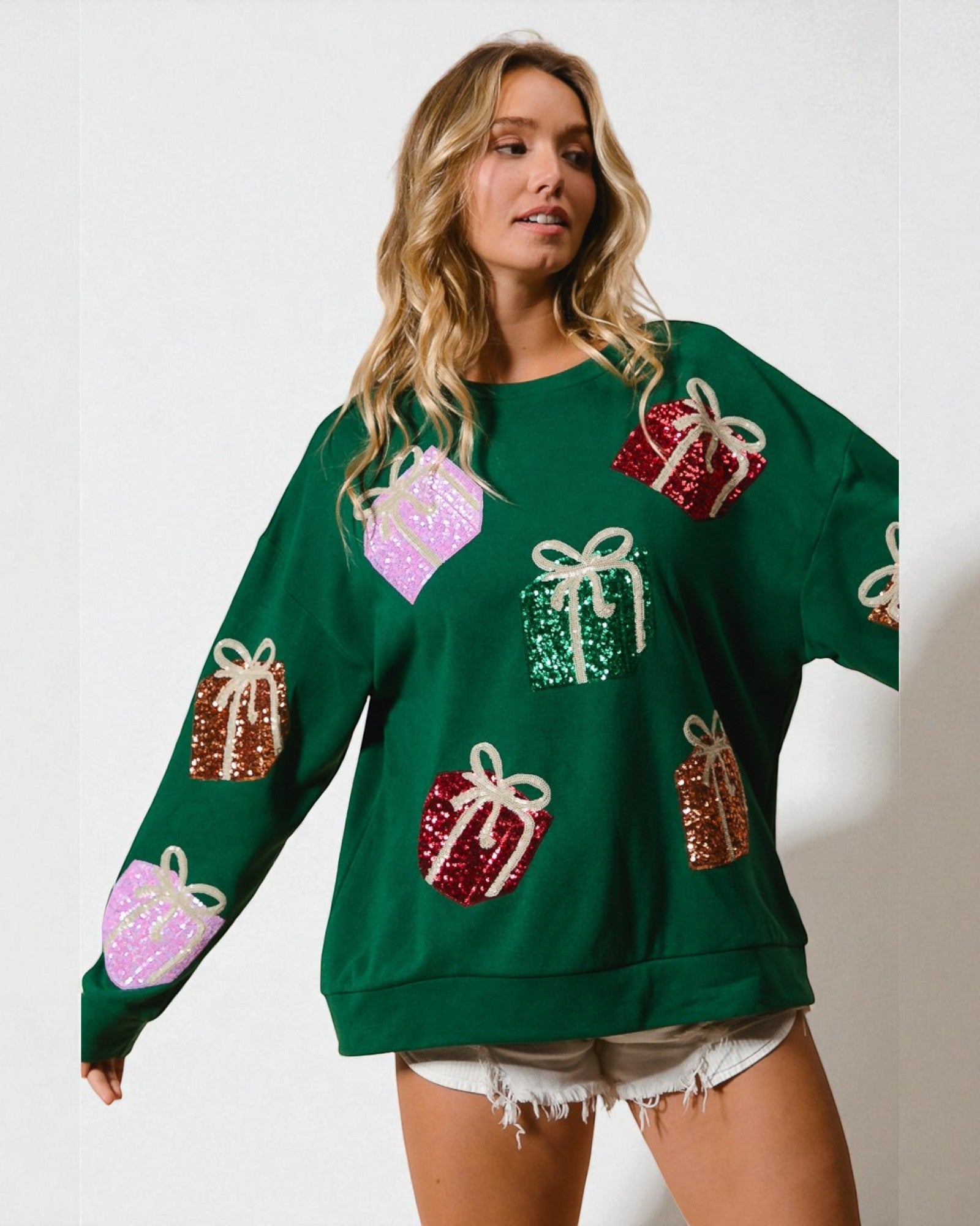 Woman wearing a green sweater with colorful gift box patterns on a white background