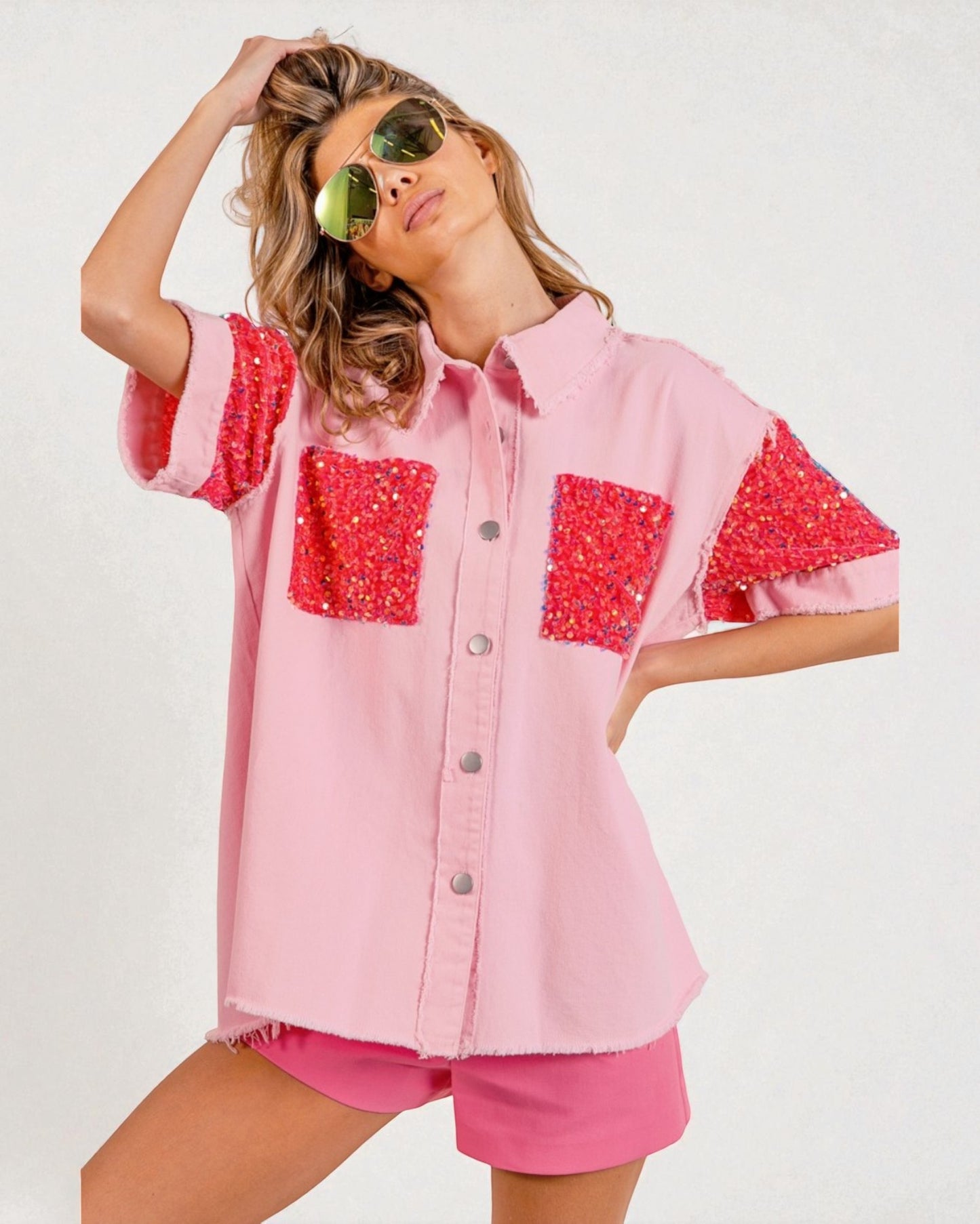 Woman wearing a pink shirt with red sequin accents and matching shorts on a white background