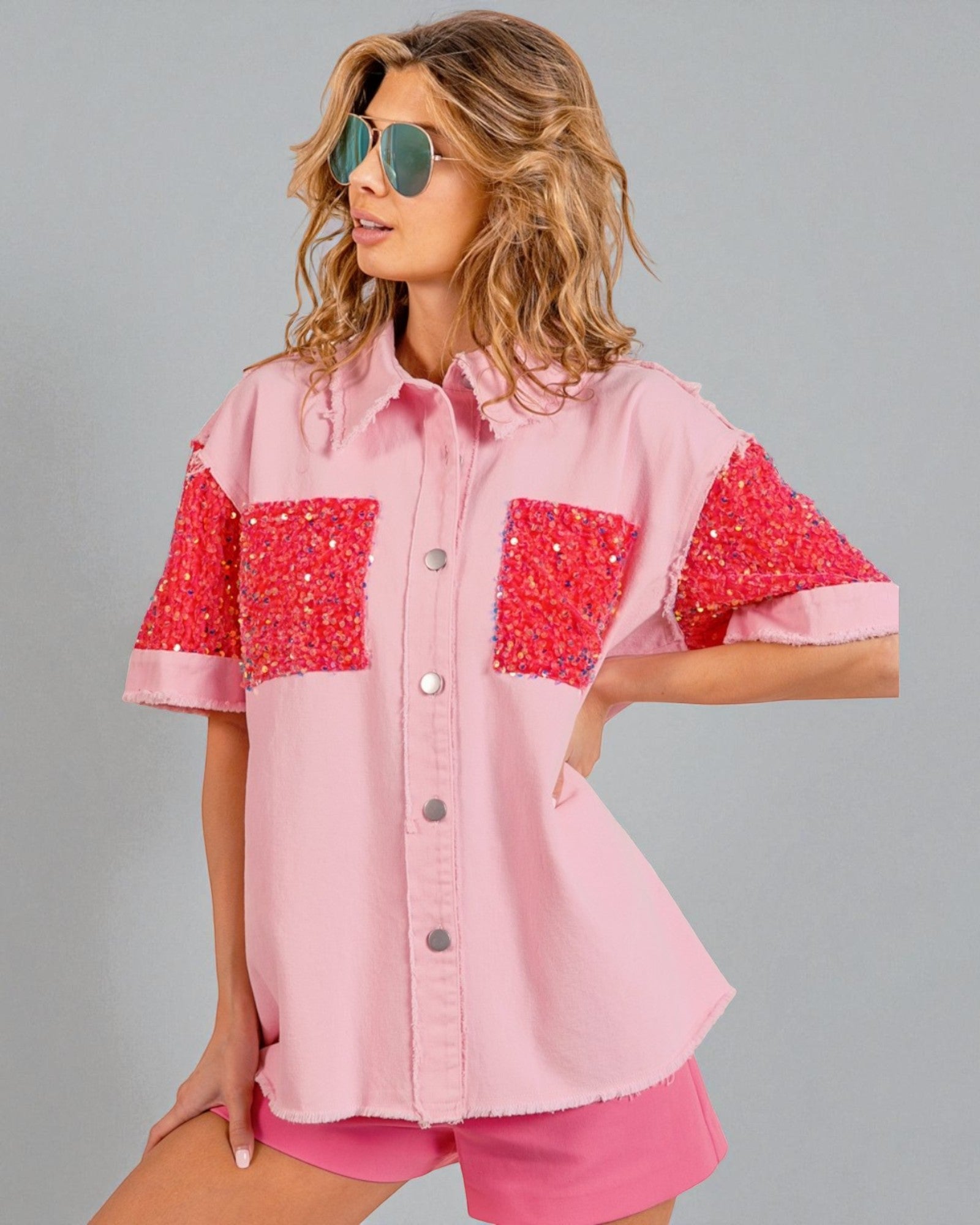 Woman wearing a pink shirt with red sequin sleeves on a gray background