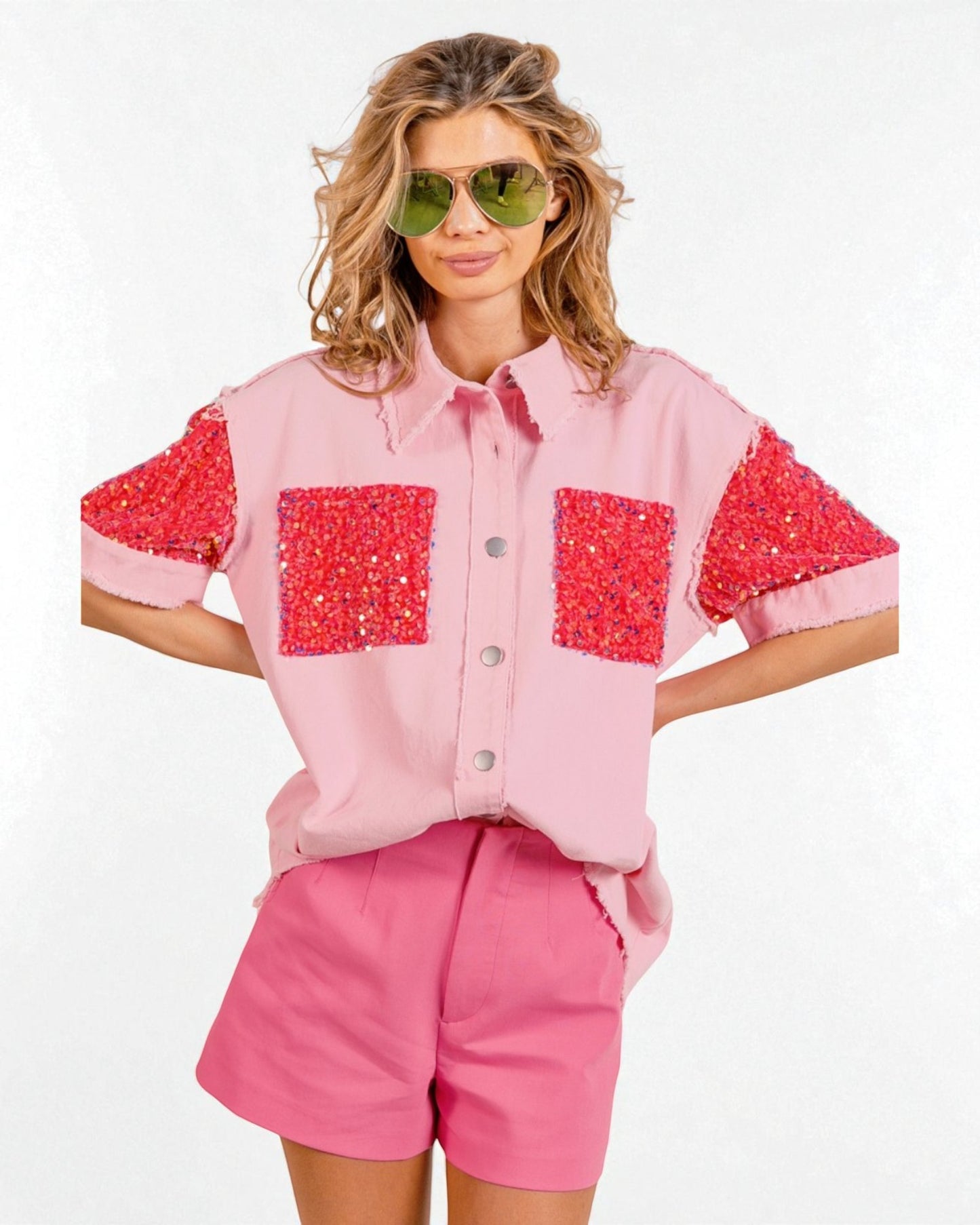 Woman wearing a pink shirt with red sequin accents and matching shorts on a white background