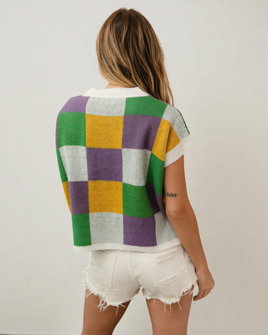 Person wearing a colorful checkered sweater and white shorts on a plain background