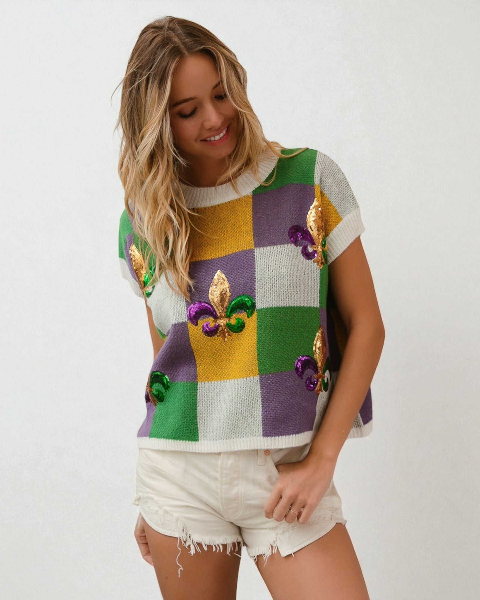 Woman wearing a colorful patterned top with white shorts on a plain background