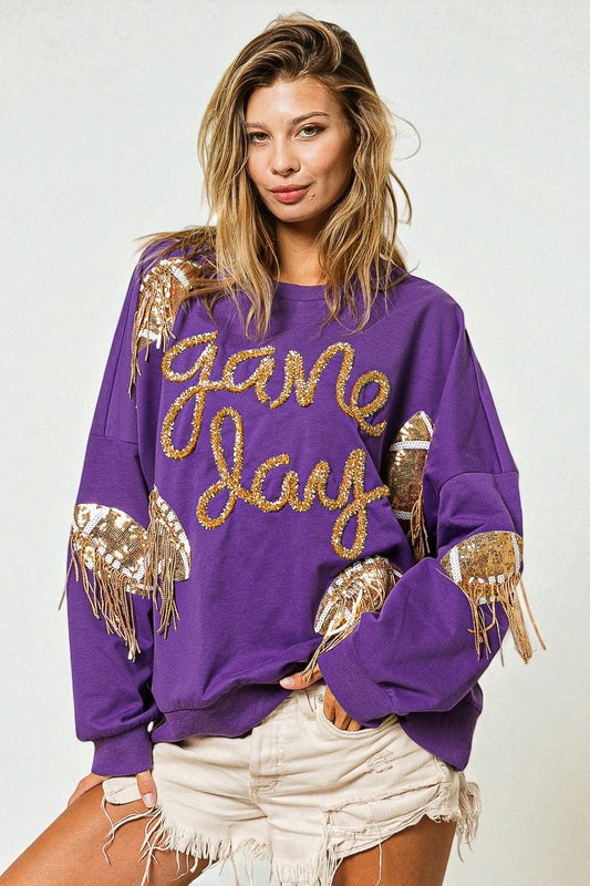 Woman wearing a purple 'game day' sweatshirt with gold fringe details on a white background