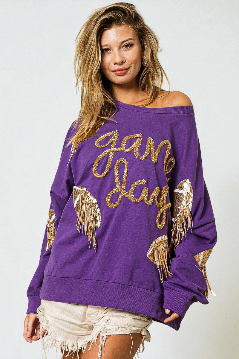 Woman wearing a purple sweatshirt with gold text and fringes on a white background