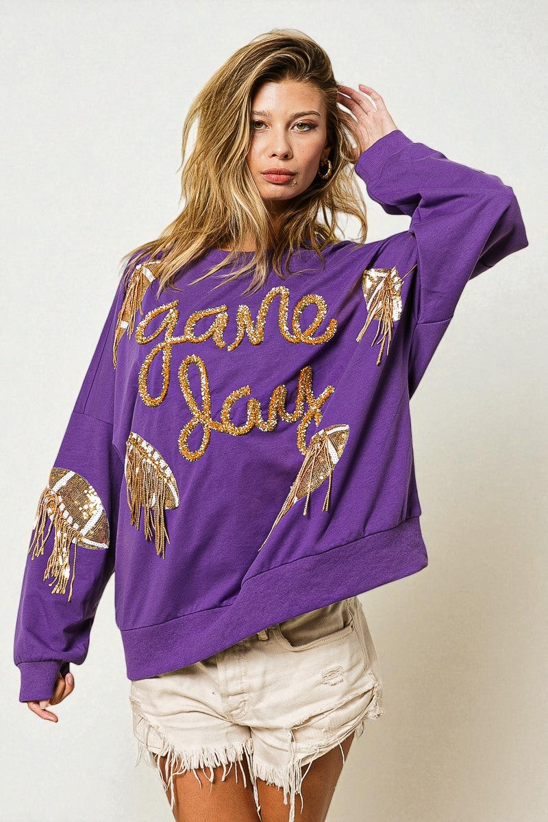 Woman wearing a purple sweatshirt with gold text and designs on a plain background