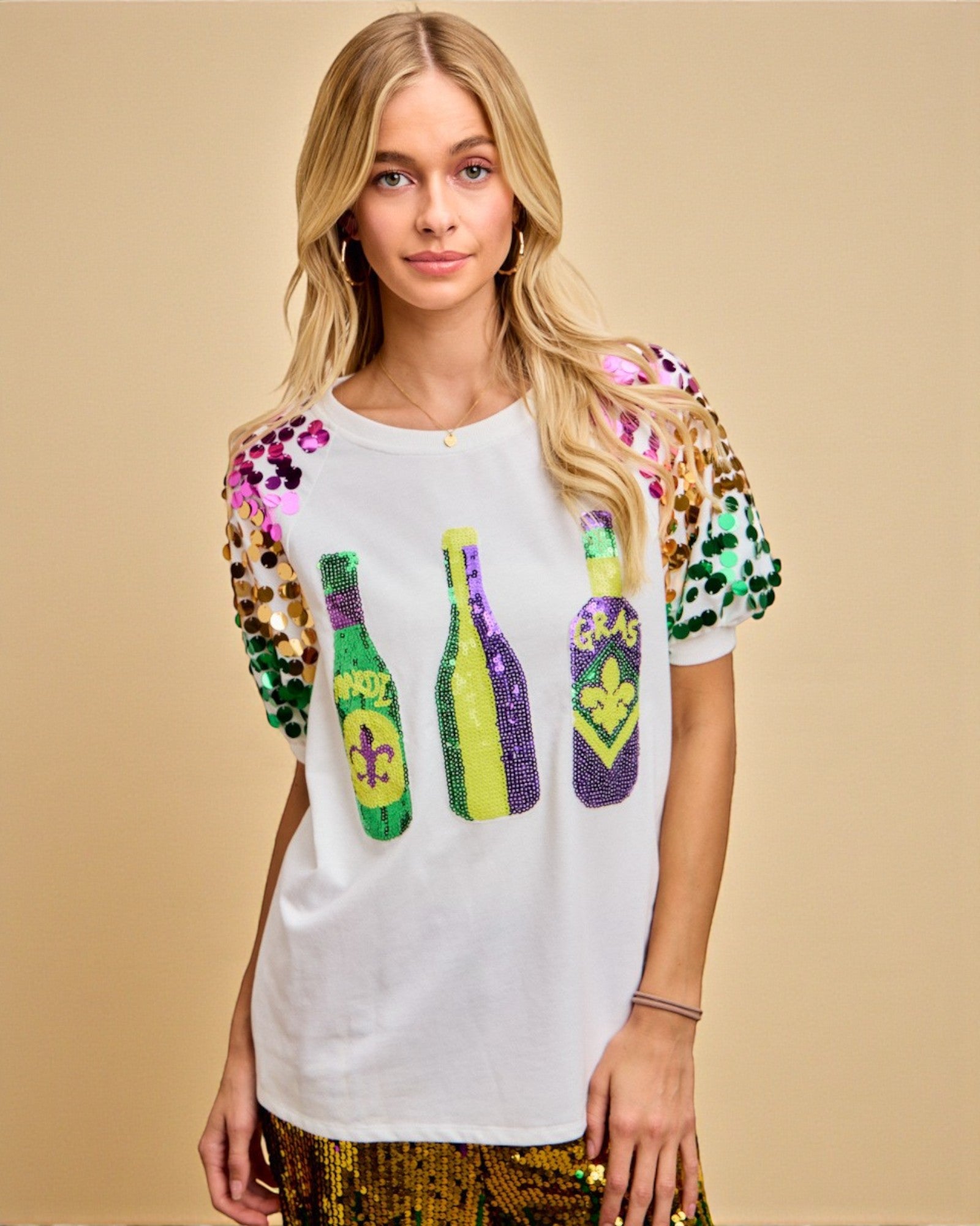 Woman wearing a white t-shirt with colorful sequin designs on a beige background