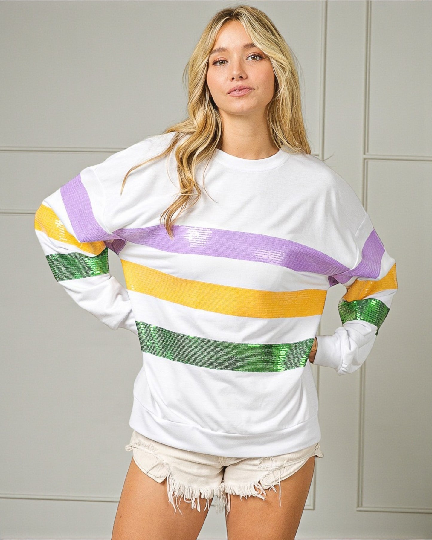 Woman wearing a white long-sleeve shirt with colorful stripes against a neutral background