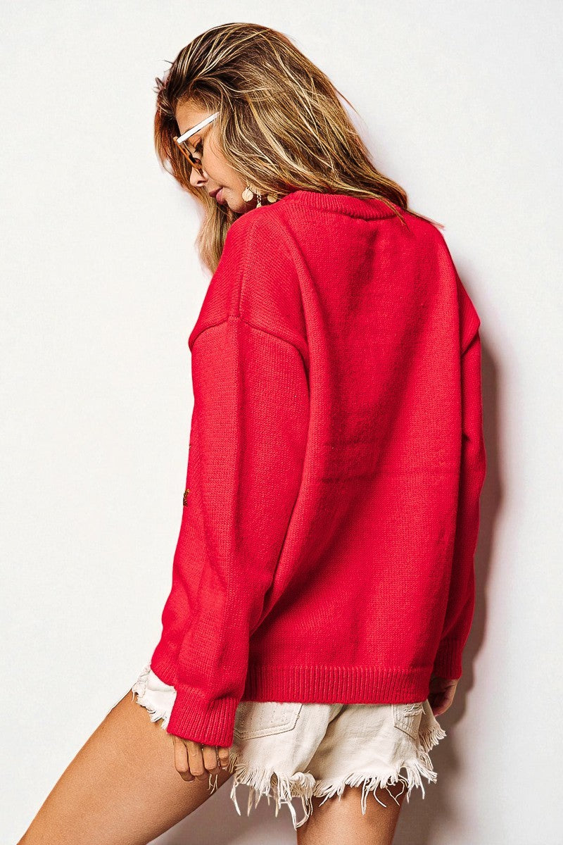 Woman wearing a red sweater and white shorts against a light background