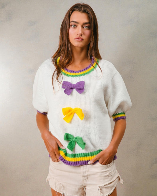 Woman wearing a colorful sweater with bows against a plain background