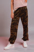 Person wearing camouflage pants with white stripes and white sneakers on a plain background