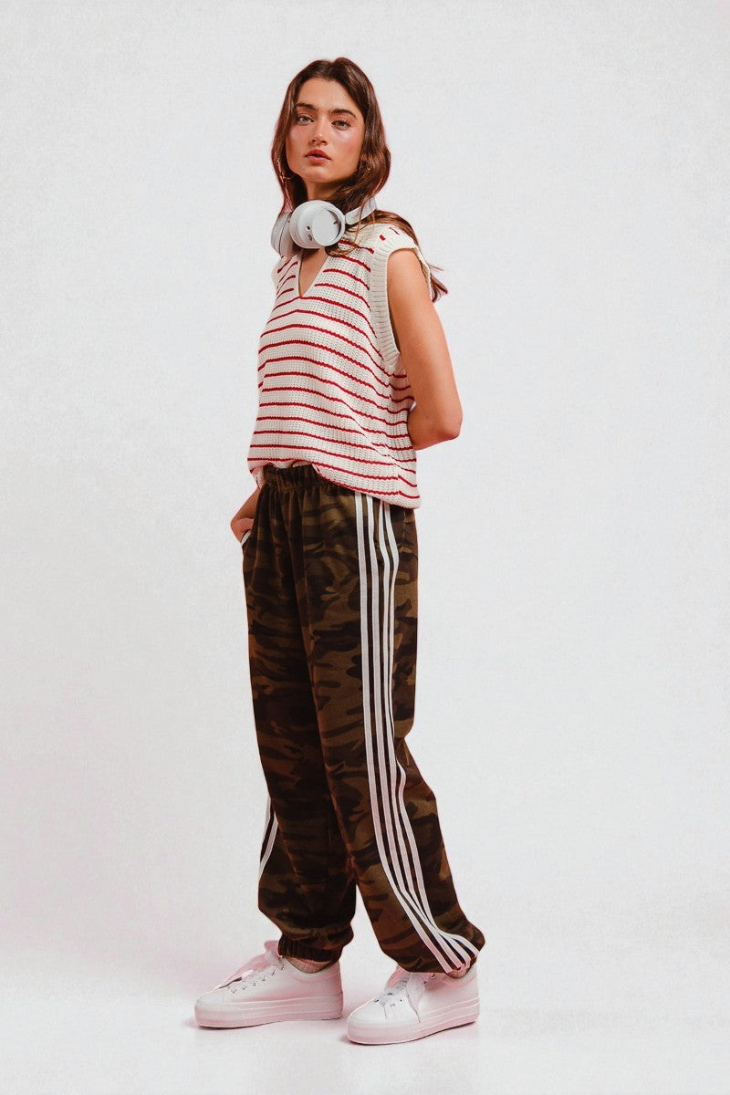 Person wearing a striped shirt, camouflage pants with white stripes, and white sneakers on a white background
