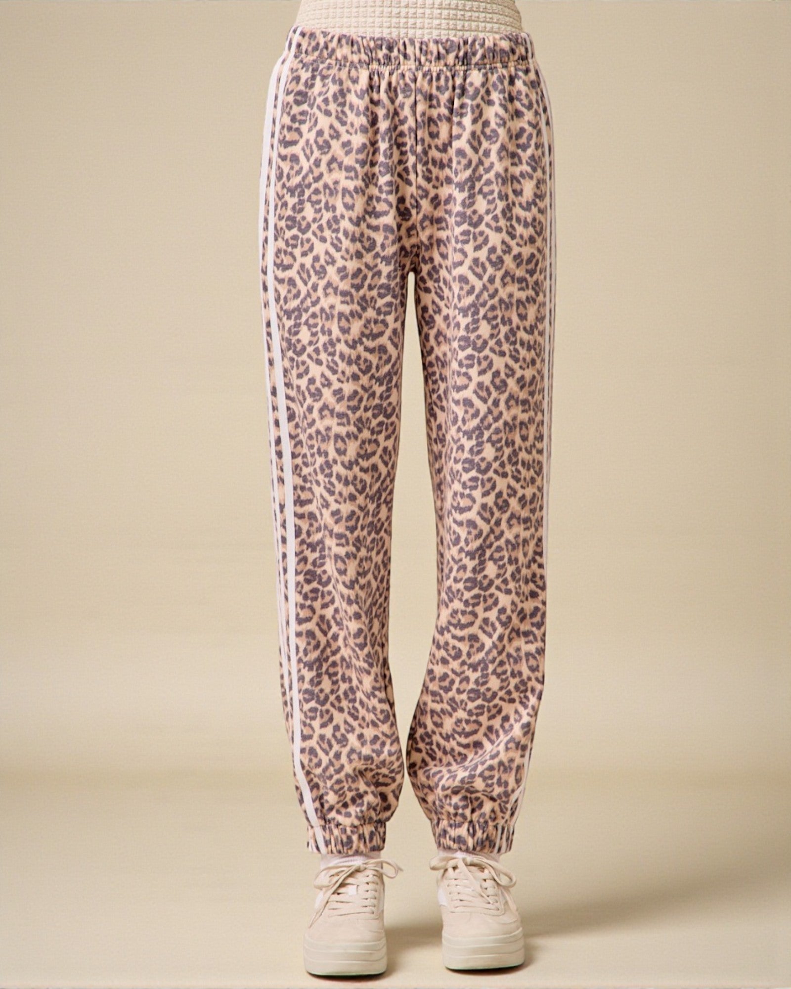 Leopard print pants with white stripes on a beige background