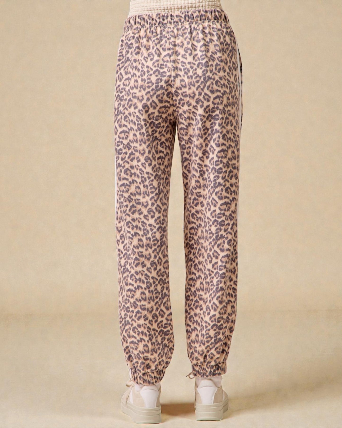 Leopard print pants worn by a person on a beige background