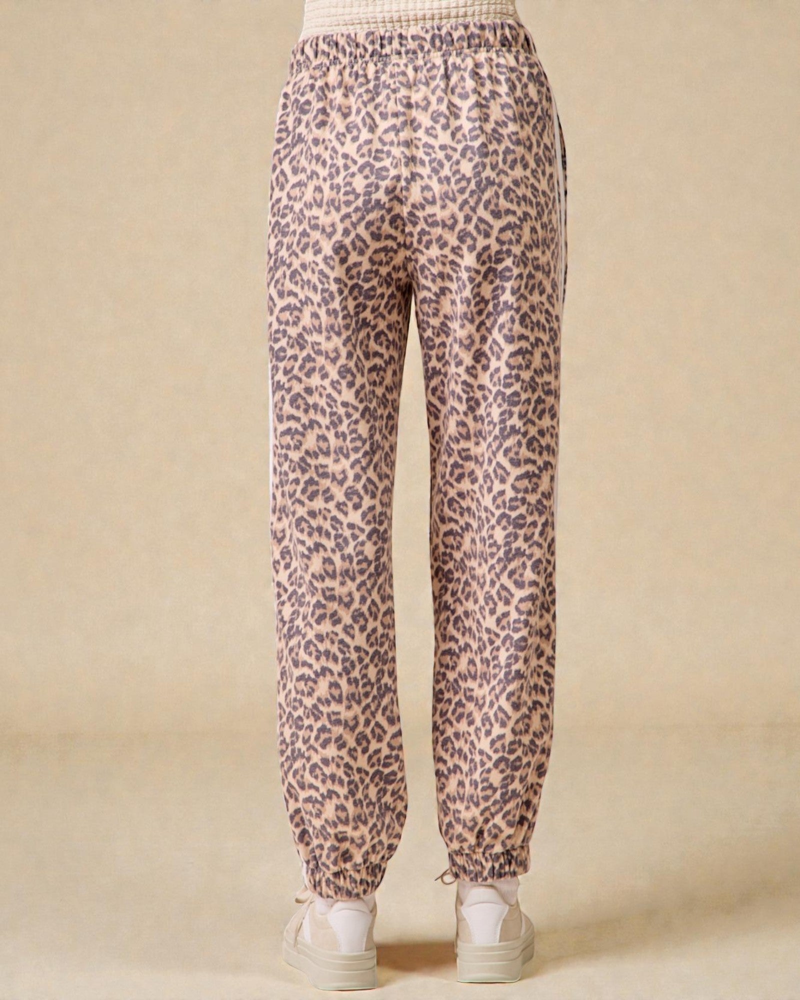 Leopard print pants worn by a person on a beige background