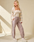 Woman wearing a white cardigan, white top, and leopard print pants on a beige background