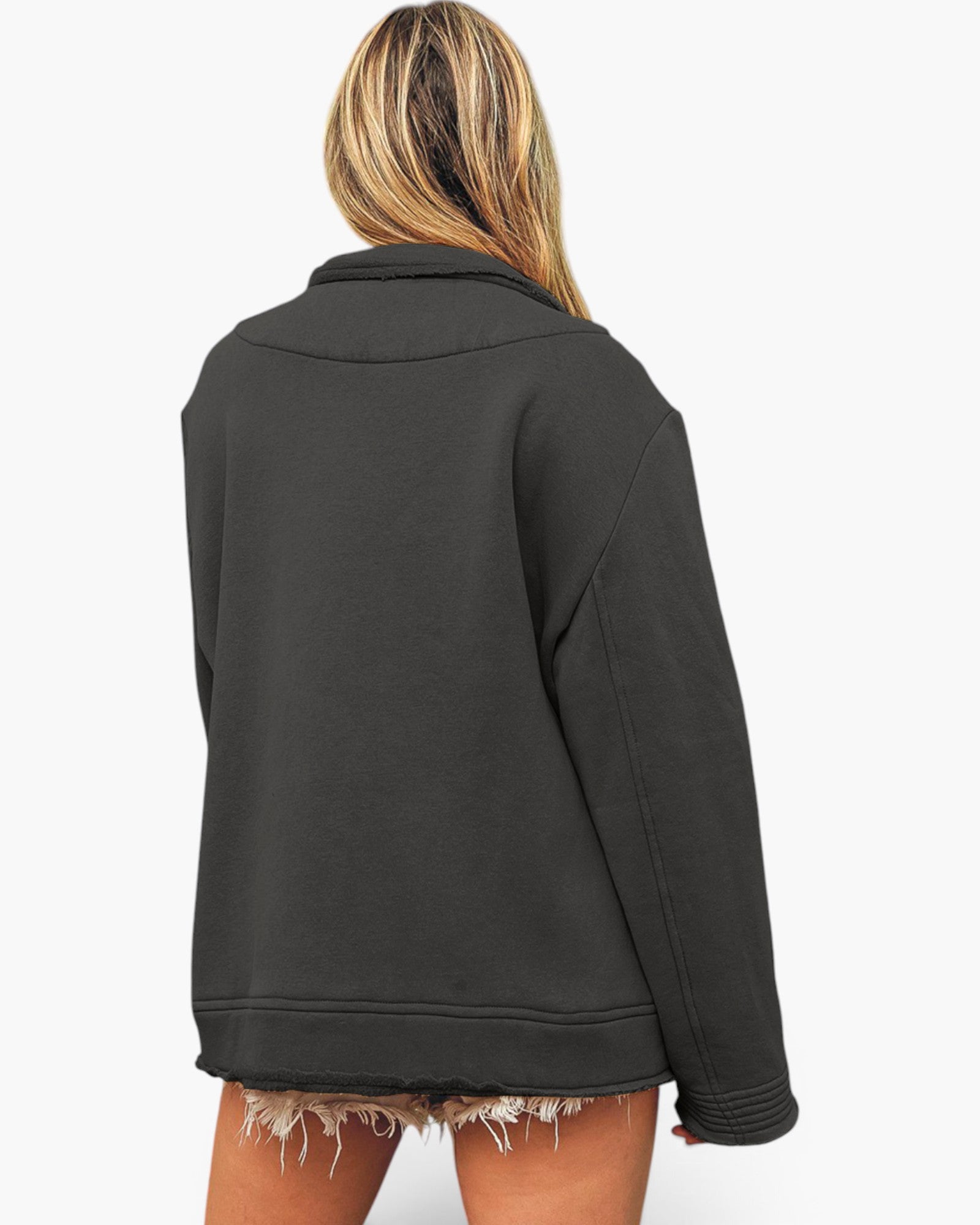 A woman shown from the back wearing an oversized black jacket with raw, frayed hems and long sleeves, paired with frayed denim shorts, against a plain white background.
