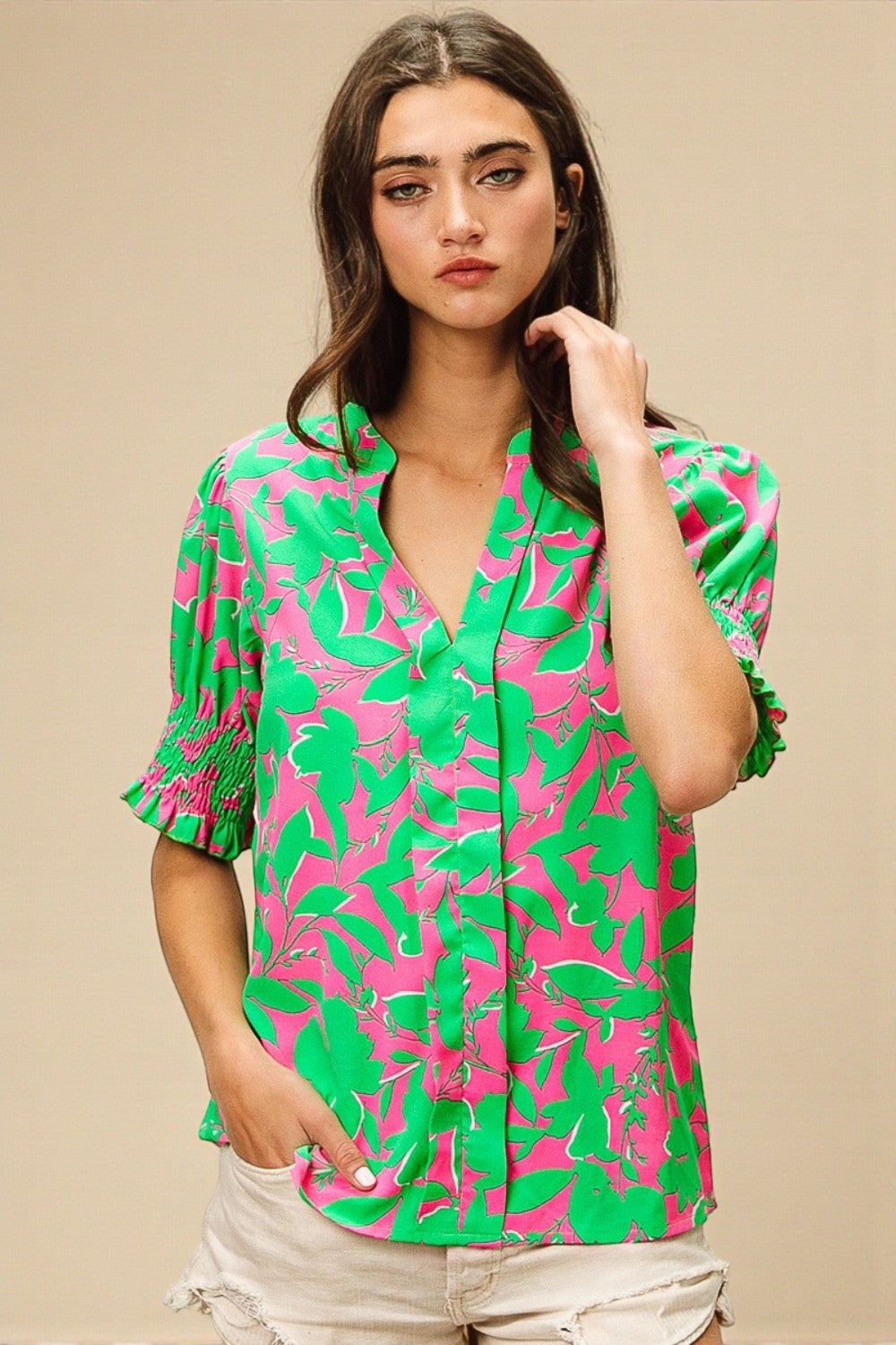 Woman wearing a green and pink patterned shirt against a beige background