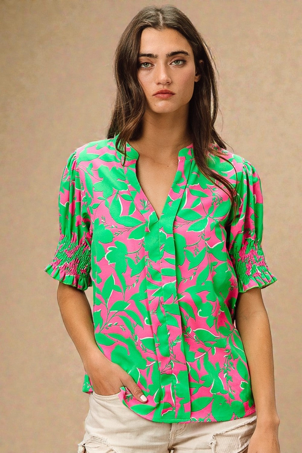 Woman wearing a green and pink patterned blouse against a beige background