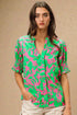 Woman wearing a green and pink patterned blouse against a beige background