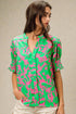 Woman wearing a pink and green patterned blouse against a beige background