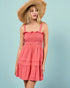 Woman wearing a coral dress and straw hat against a light blue background