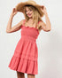 Woman wearing a coral dress and straw hat on a white background