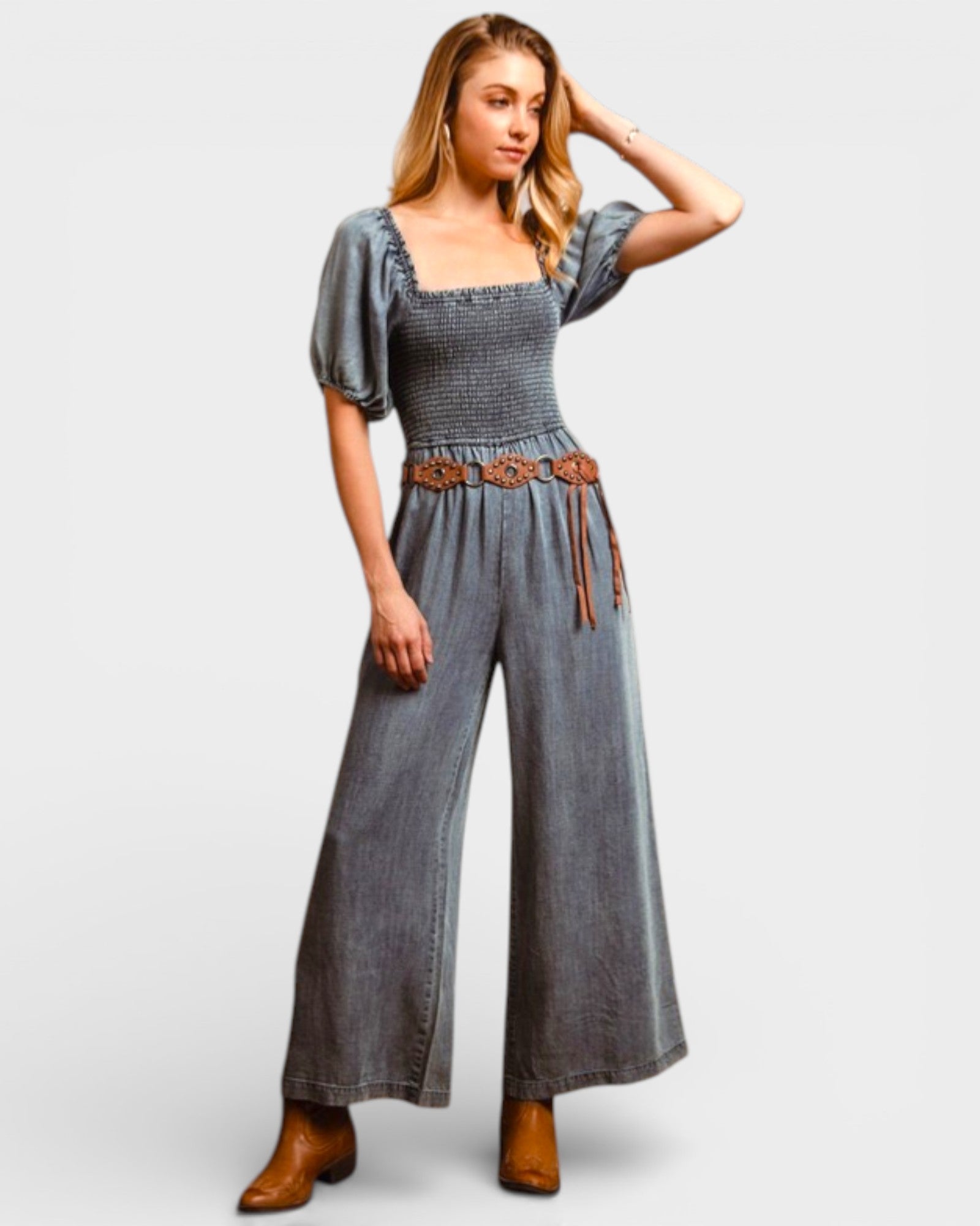 Woman wearing a denim jumpsuit with a belt on a white background