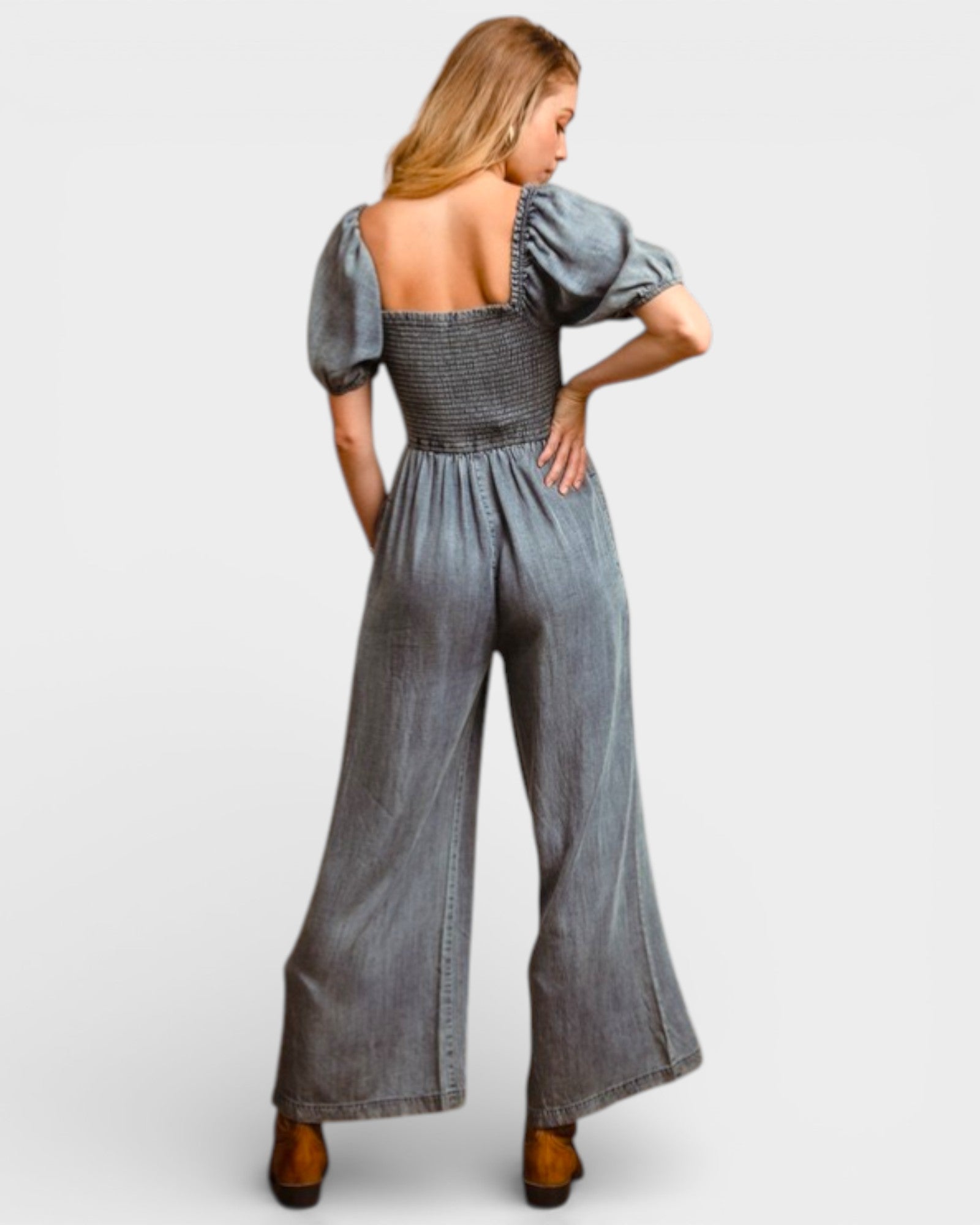 Woman wearing a denim jumpsuit with puff sleeves on a white background