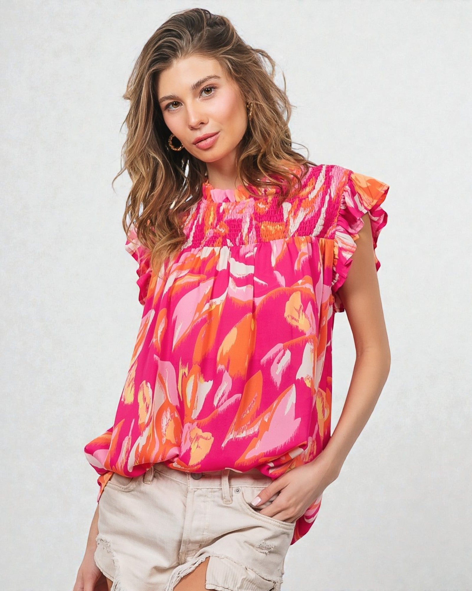 Woman wearing a colorful floral blouse with ruffled sleeves on a light background