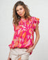 Woman wearing a colorful floral blouse with ruffled sleeves on a light background